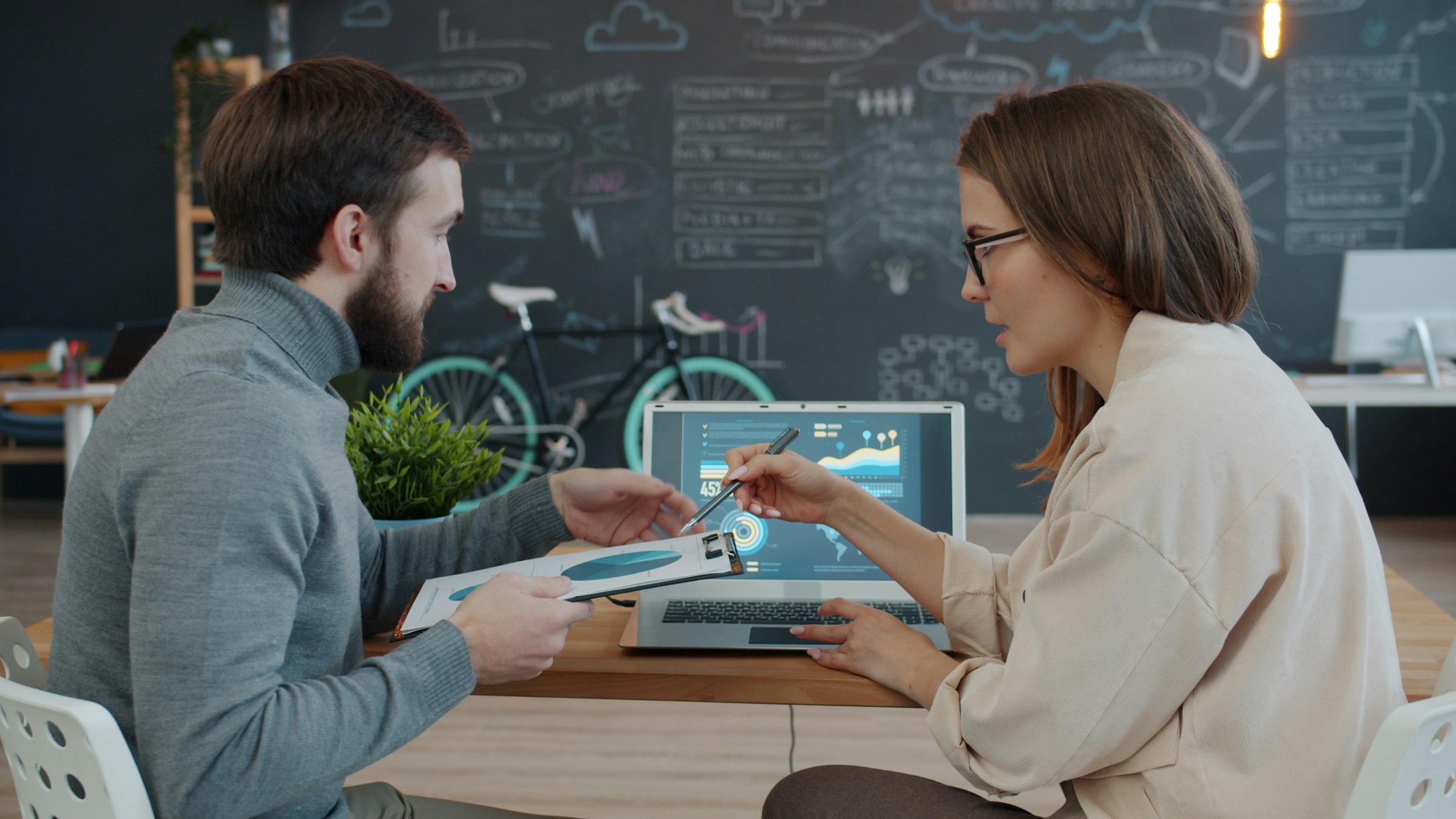 Two colleagues reviewing performance data on a laptop — the kind of collaborative results review DEM enables for clients.